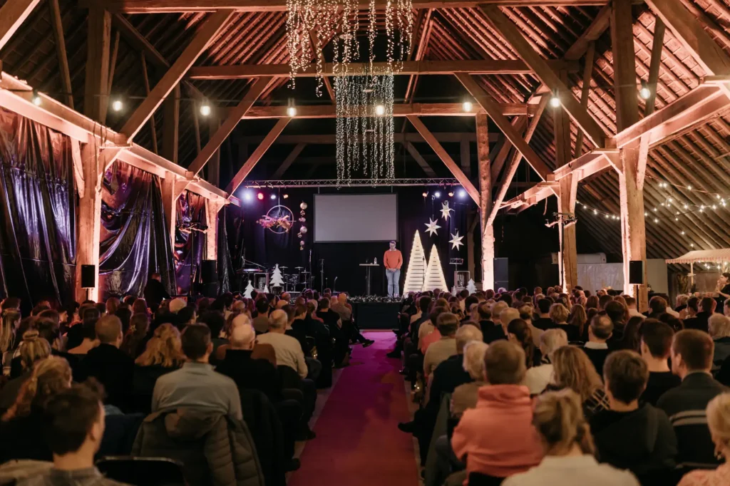 Kerstnachtdienst in schuur met voorganger op het podium